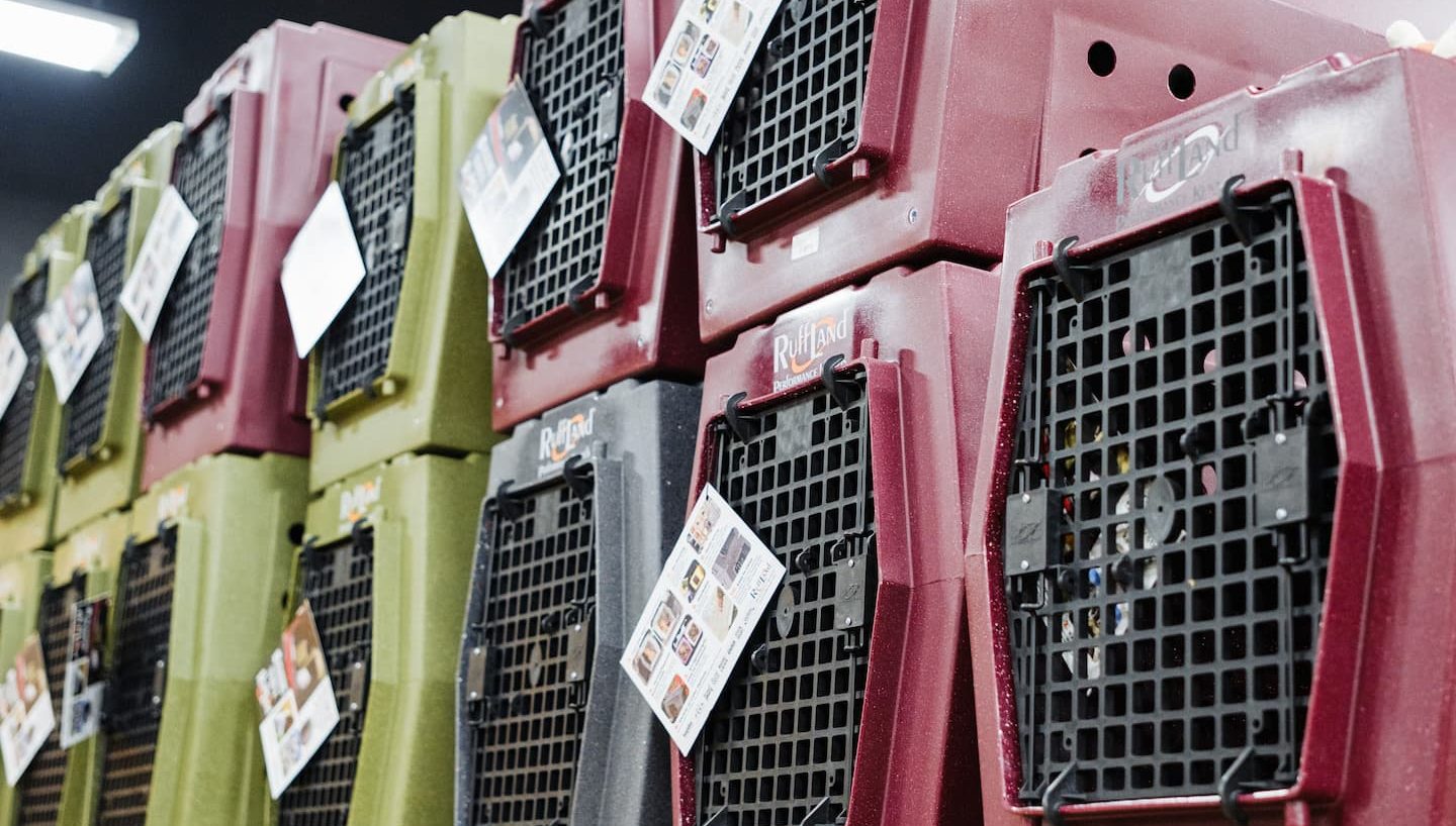 Stack of Ruff Land Performance Kennels in red, green, and gray displayed at Anderson’s General Store, showing durable, high-quality dog crates ideal for hunting dogs and outdoor adventures.