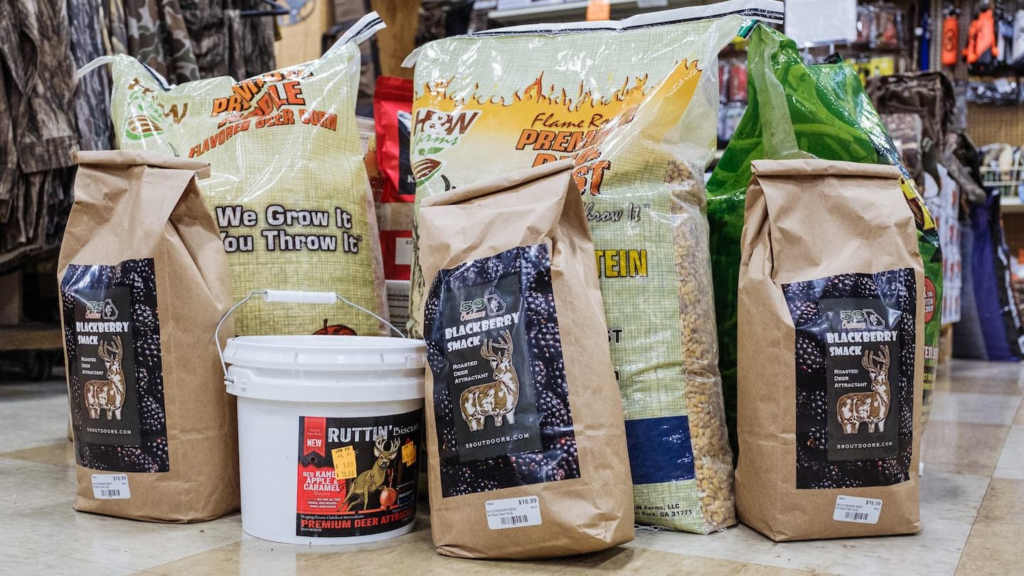 Bags of deer attractant feed including Blackberry Smack and Ruttin’ Biscuits displayed at Anderson’s General Store in Statesboro, Georgia, featuring hunting supplies and attractants for deer season.”
