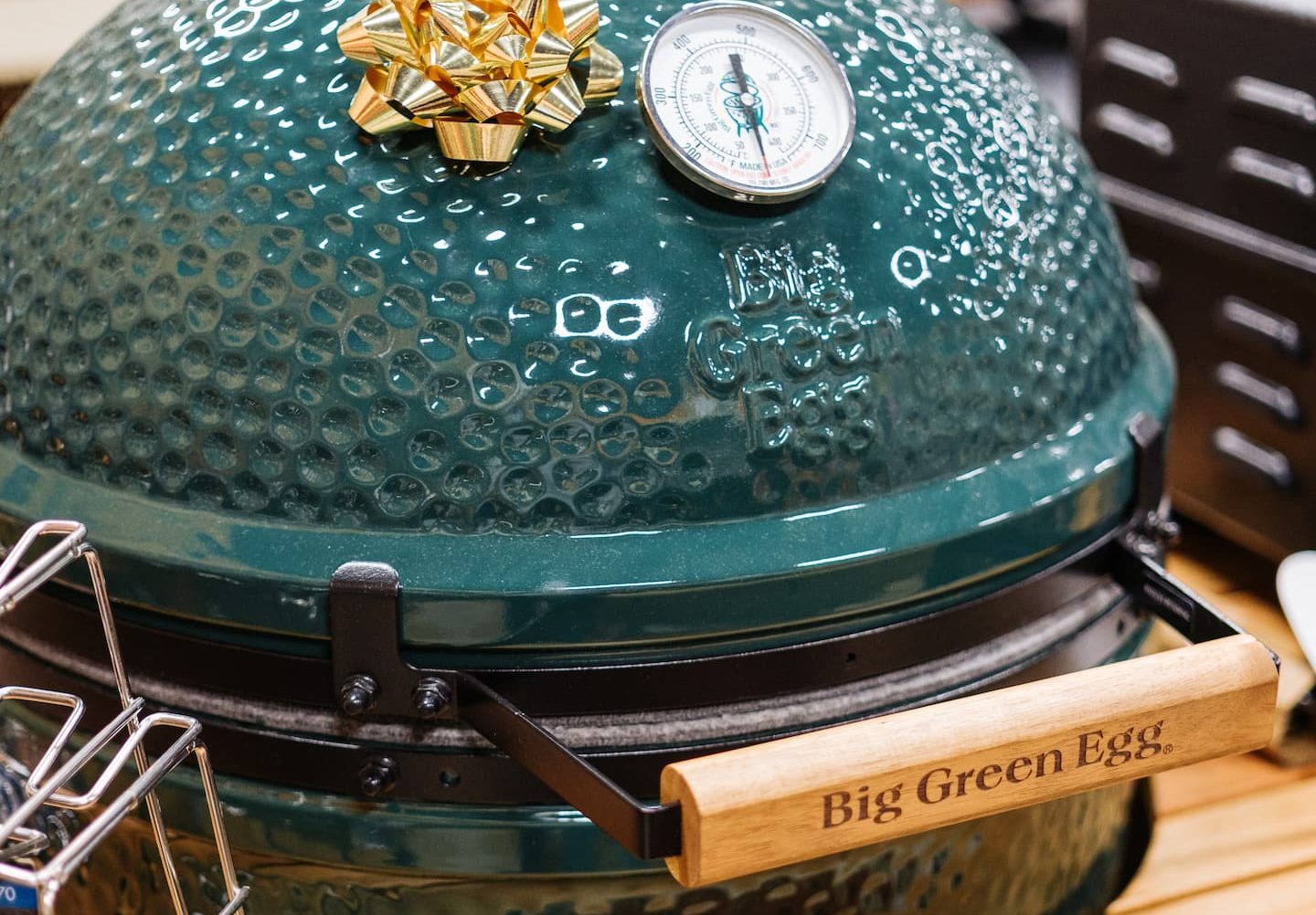 Big Green Egg ceramic grill on display at Anderson’s General Store, featuring a gold holiday bow and built-in temperature gauge on its signature green dome lid.