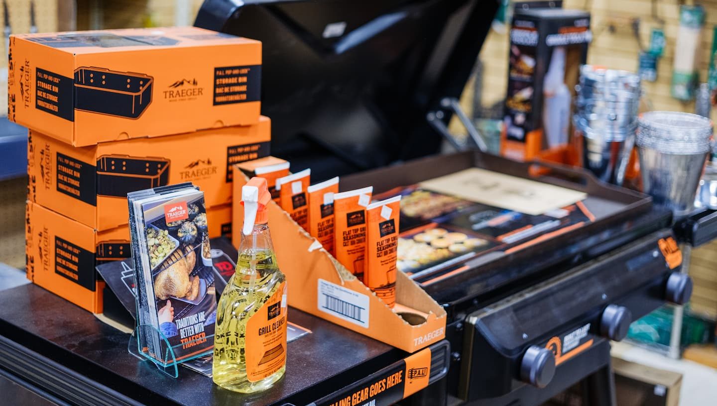 Traeger grill display at Anderson’s General Store featuring grilling gear, cleaner spray, storage bins, and flat top seasoning accessories.