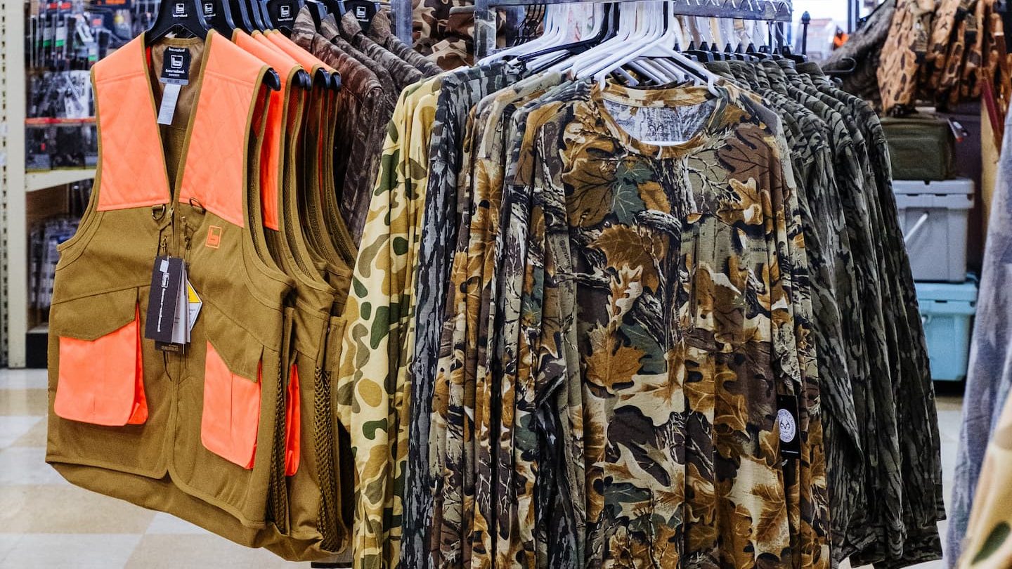 Display of camo hunting apparel and blaze orange vests at Anderson’s General Store in Statesboro, Georgia, featuring outdoor and hunting gear for every season.